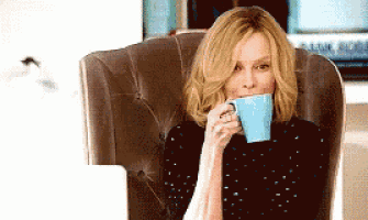 a woman sits in a chair drinking a cup of coffee