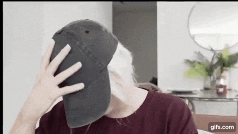 a man is covering his face with a baseball cap