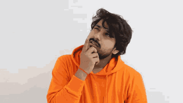 a man with a beard is wearing a bright orange hoodie