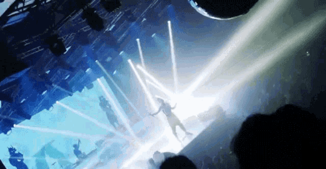 a woman is dancing on a stage in front of a crowd at a concert in a dark room .