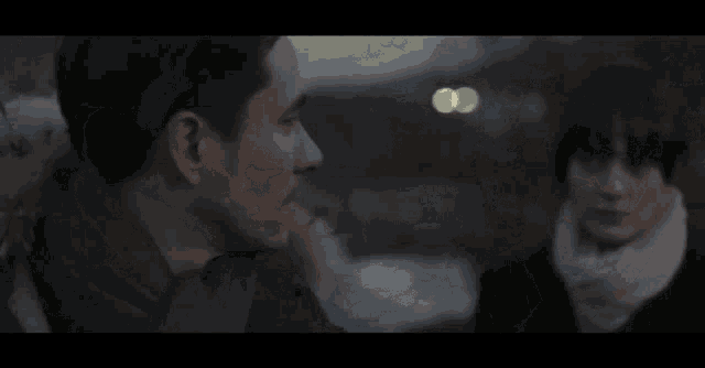 a man and a woman are looking at each other through a window in a dark room .