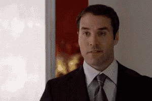 a man in a suit and tie is standing in a room .