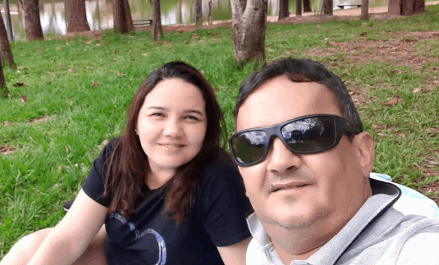 a man and a woman are posing for a selfie in the grass