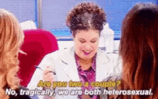 a woman is sitting at a table with two women and talking to them about being heterosexual .