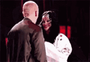 a man and a woman are standing next to each other and the woman has blood on her face .