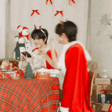a couple of people dressed in santa costumes are standing around a table