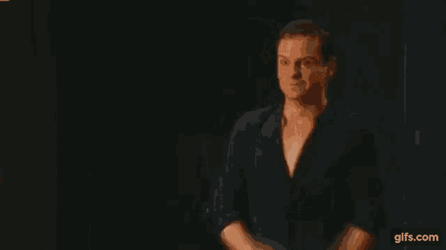 a man in a black shirt is dancing on a stage in front of a black background .