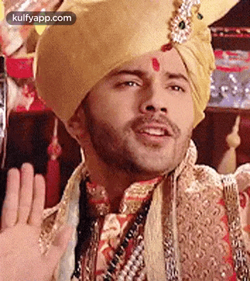 a man wearing a turban and a beard is waving .
