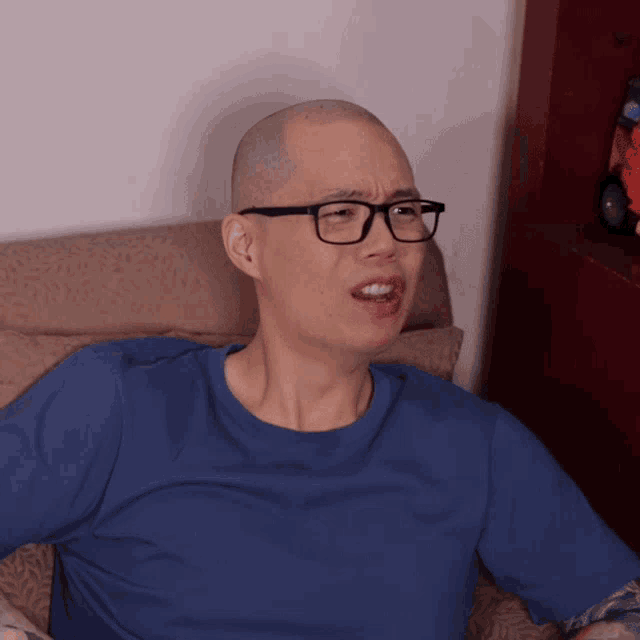 a bald man wearing glasses and a blue shirt