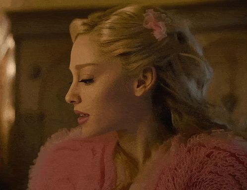 a close up of a woman wearing a pink ruffled dress