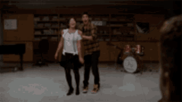 a man and a woman are dancing on a stage in front of a drum set