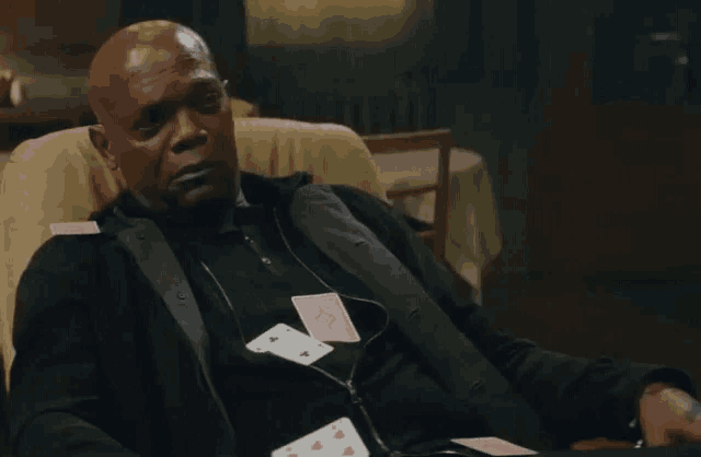 a man is sitting in a chair with playing cards on his chest