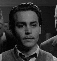 a black and white photo of a man wearing a tie and vest