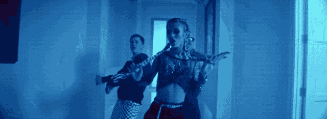 a woman in a crop top is dancing in a hallway