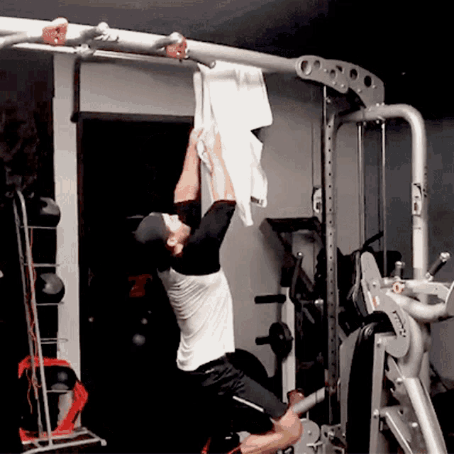 a man hangs a towel from a bar in a gym while wearing a black hat