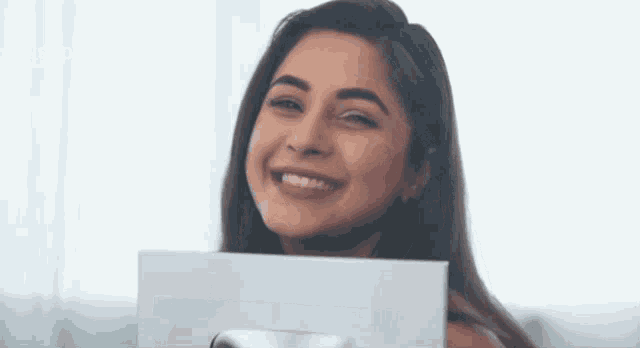 a woman is smiling while holding a piece of paper in front of her face ..