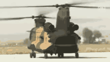 a military helicopter is parked on a runway