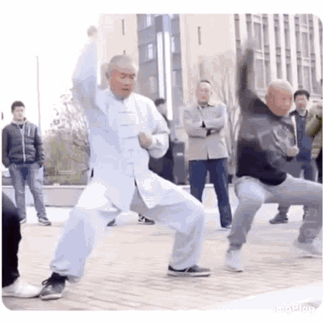 a group of older men are practicing martial arts on a sidewalk .