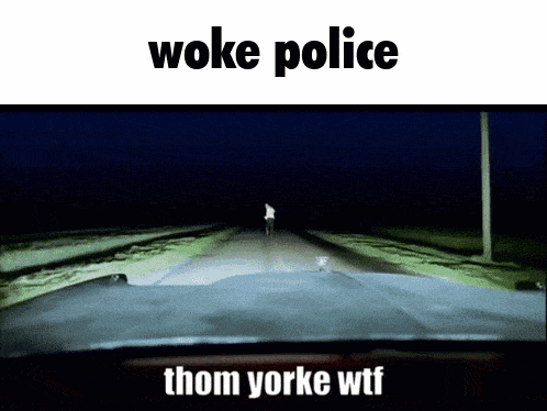 woke police thom yorke wtf is written above a car driving down a road at night