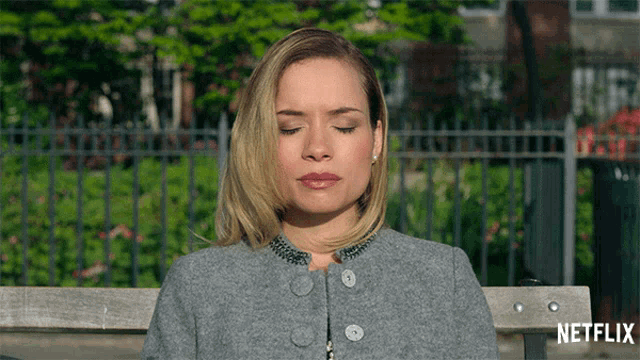 a woman is sitting on a bench with her eyes closed and a netflix logo in the background