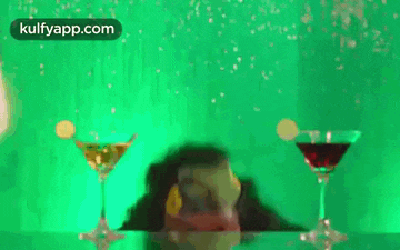 a man is swimming in a pool with two martini glasses on the table .