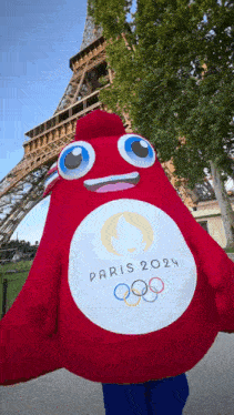 a mascot for the paris 2024 olympics is in front of the eiffel tower