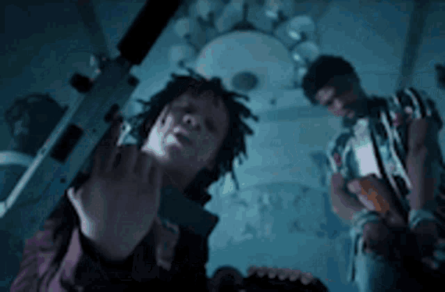 a man is holding a gun and giving the middle finger while another man looks on .