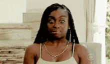 a woman in a white tank top is making a funny face .
