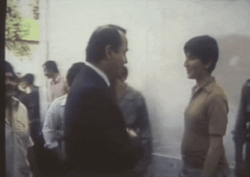 a man in a suit and tie is talking to another man