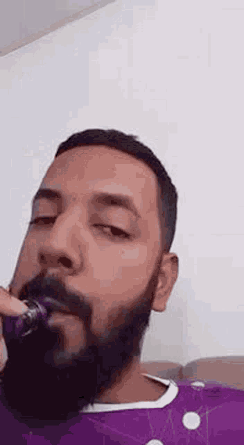 a man with a beard is brushing his teeth with a toothbrush while sitting on a couch .