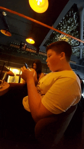 a young boy sitting at a table looking at his phone