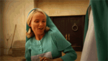a woman in a green nurse 's uniform is standing in front of a door