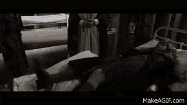 a man is laying in a hospital bed while a nurse stands behind him .