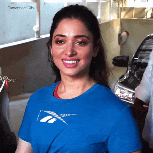 a woman wearing a blue reebok t-shirt is smiling
