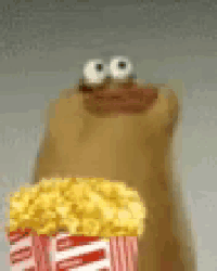 a stuffed animal with big eyes is holding a bag of popcorn