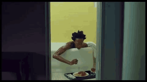 a man is laying in a bathtub eating spaghetti with a fork .