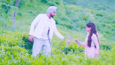 a man and a woman are standing in a lush green field