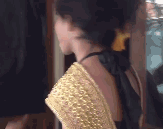 a woman in a black and gold dress is standing in front of a door