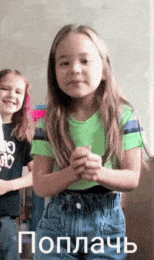 a little girl in a green shirt and blue shorts is clapping