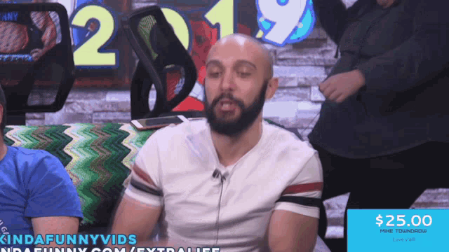 a man is sitting in front of a sign that says kindafunnyvids