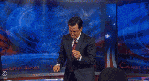 a man in a suit and tie stands in front of a comedy central screen