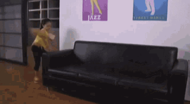 a woman is standing in front of a couch with a jazz poster on the wall