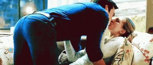 a man and woman are kissing on a bed .