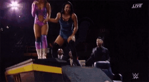 two women are holding hands on a stage in a wrestling ring .