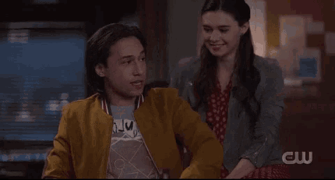 a man in a yellow jacket is pointing at a woman in a grey jacket