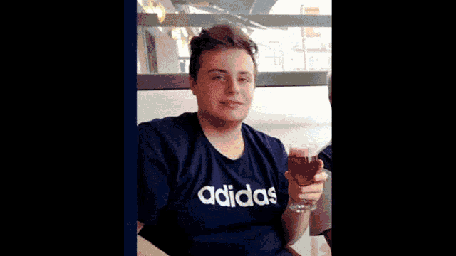 a man wearing an adidas shirt holds a wine glass