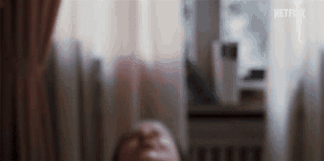 a woman is laying on a bed with her eyes closed and a netflix logo in the background .