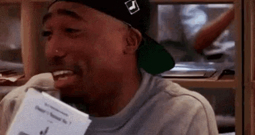 a close up of a man wearing a hat and holding a piece of paper .