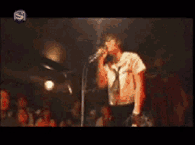 a blurry picture of a man singing into a microphone with the letter s on the bottom