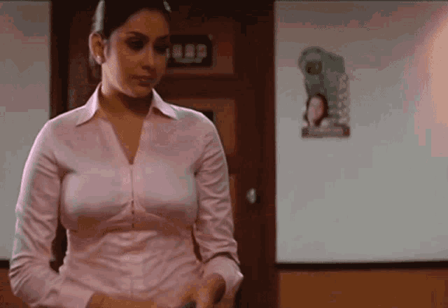 a woman in a pink shirt is standing in front of a wall with a picture of a woman in a green shirt